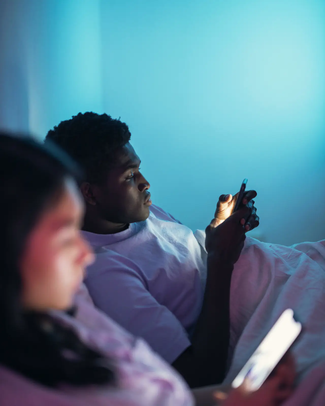 Two people on their phones in a dark room